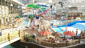 Ein großer Indoor-Wasserpark mit mehreren Pools, Rutschen und Essbereichen.