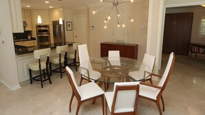 A modern kitchen with stainless steel appliances, a glass dining table surrounded by chairs, and a unique chandelier. - Lido Key Home w Pool Near Beach & Shops: Rondy Home by RVA (Sarasota)