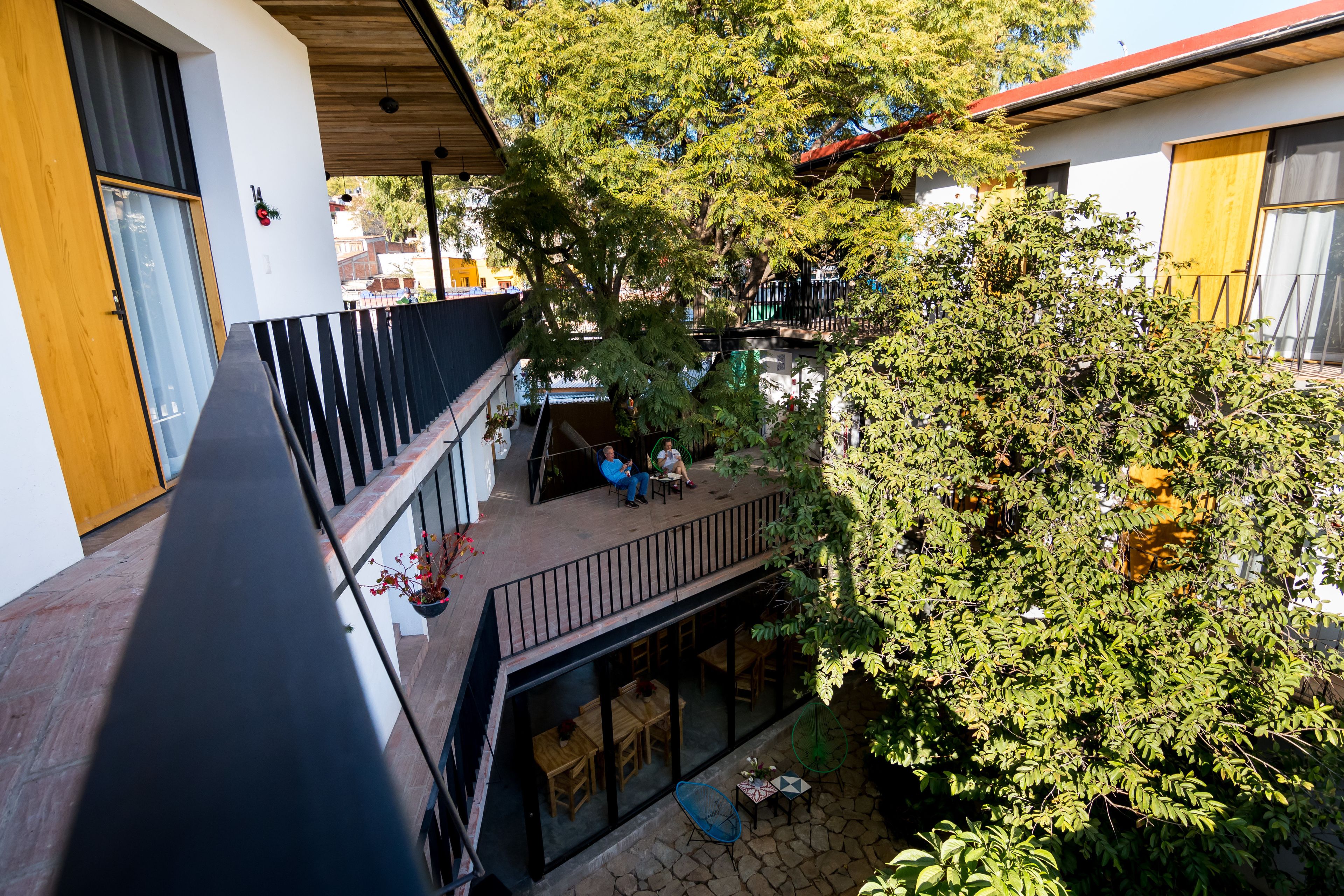 A courtyard with a wooden deck, outdoor seating, and a large tree providing shade.