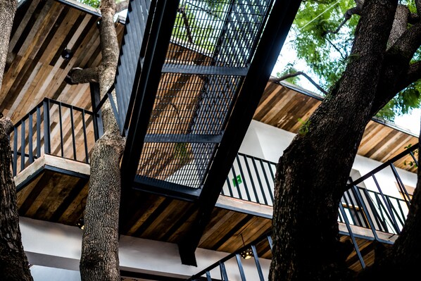 A multi-level wooden staircase with metal railings, surrounded by trees. - Hotel con Corazón Oaxaca (Oaxaca)