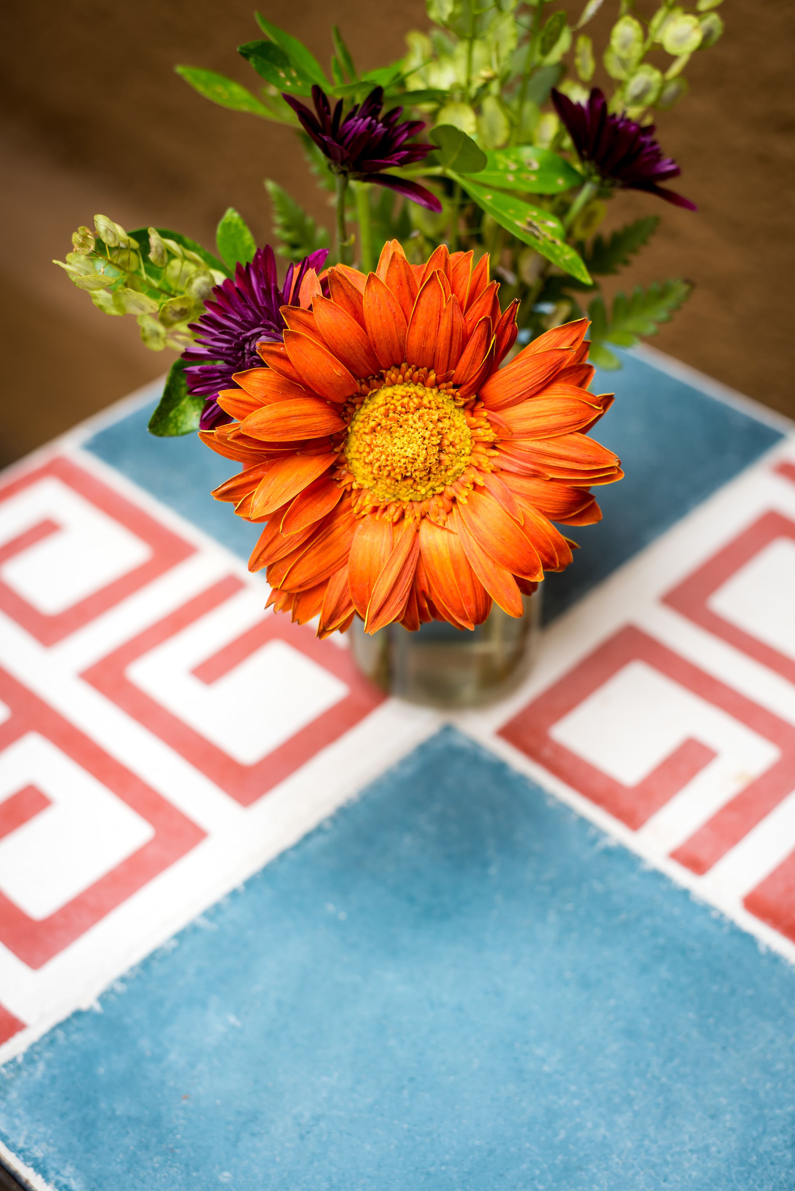 A vase with flowers on a table with a geometric patterned tablecloth.