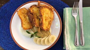 Un plato con pan tostado, rodajas de plátano y un pequeño adorno sobre un camino de mesa tejido azul.