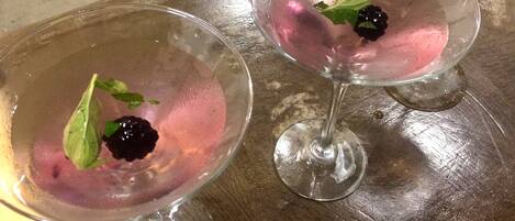 Two glasses of pink beverage with blackberries and mint leaves on a wooden surface.