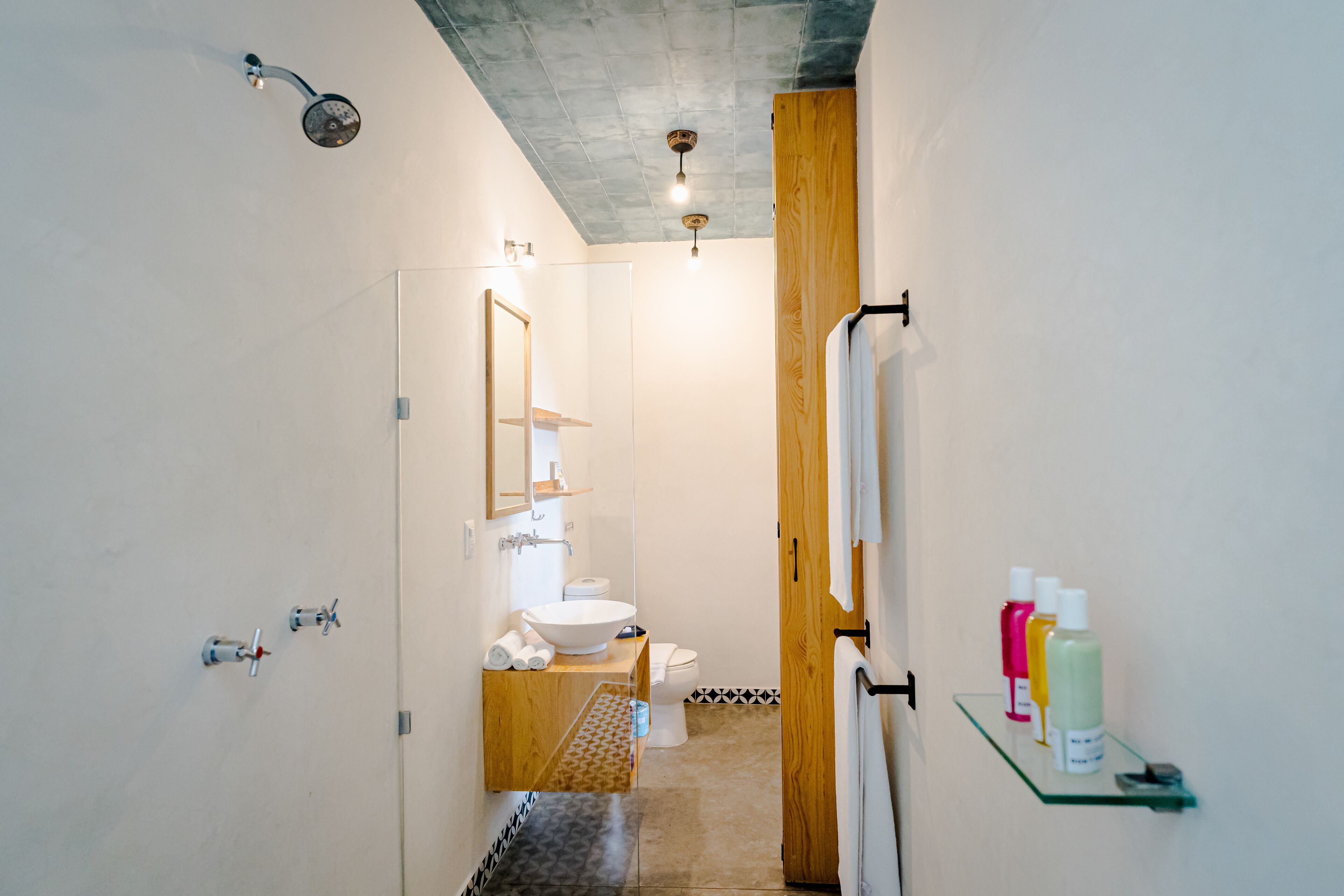 Un baño moderno con cabina de ducha de vidrio, tocador de madera y un inodoro.