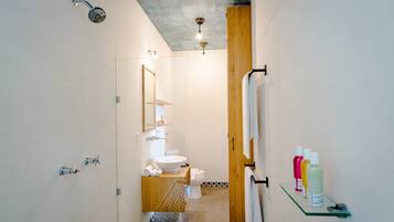 Un baño moderno con cabina de ducha de vidrio, tocador de madera y un inodoro.
