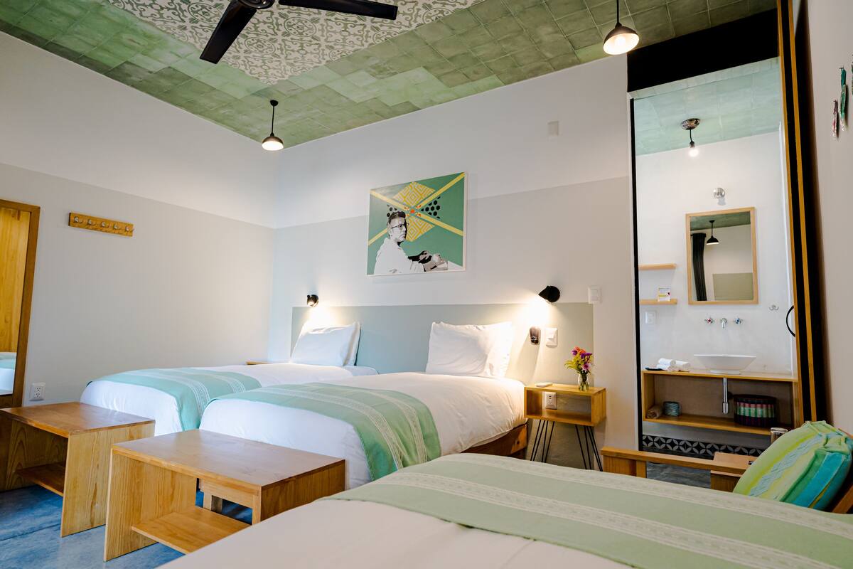 A hotel room with two beds, a wooden nightstand, a mirror, and a wall-mounted artwork.