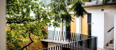 A modern building with a wooden door, a staircase, and a balcony with a black railing.