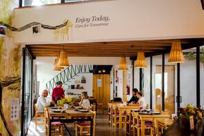 Enjoy meals in a contemporary dining area with wooden tables and chairs, featuring a welcoming sign.