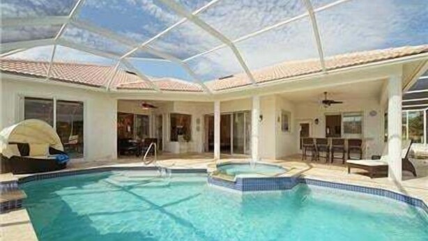 A pool area with a clear blue pool, a covered patio, and a boat shelter.