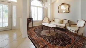 A spacious living room with a large rug, two sofas, a coffee table, and a chandelier.