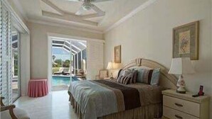 A bedroom with a bed, bedside table, and a view of a pool.