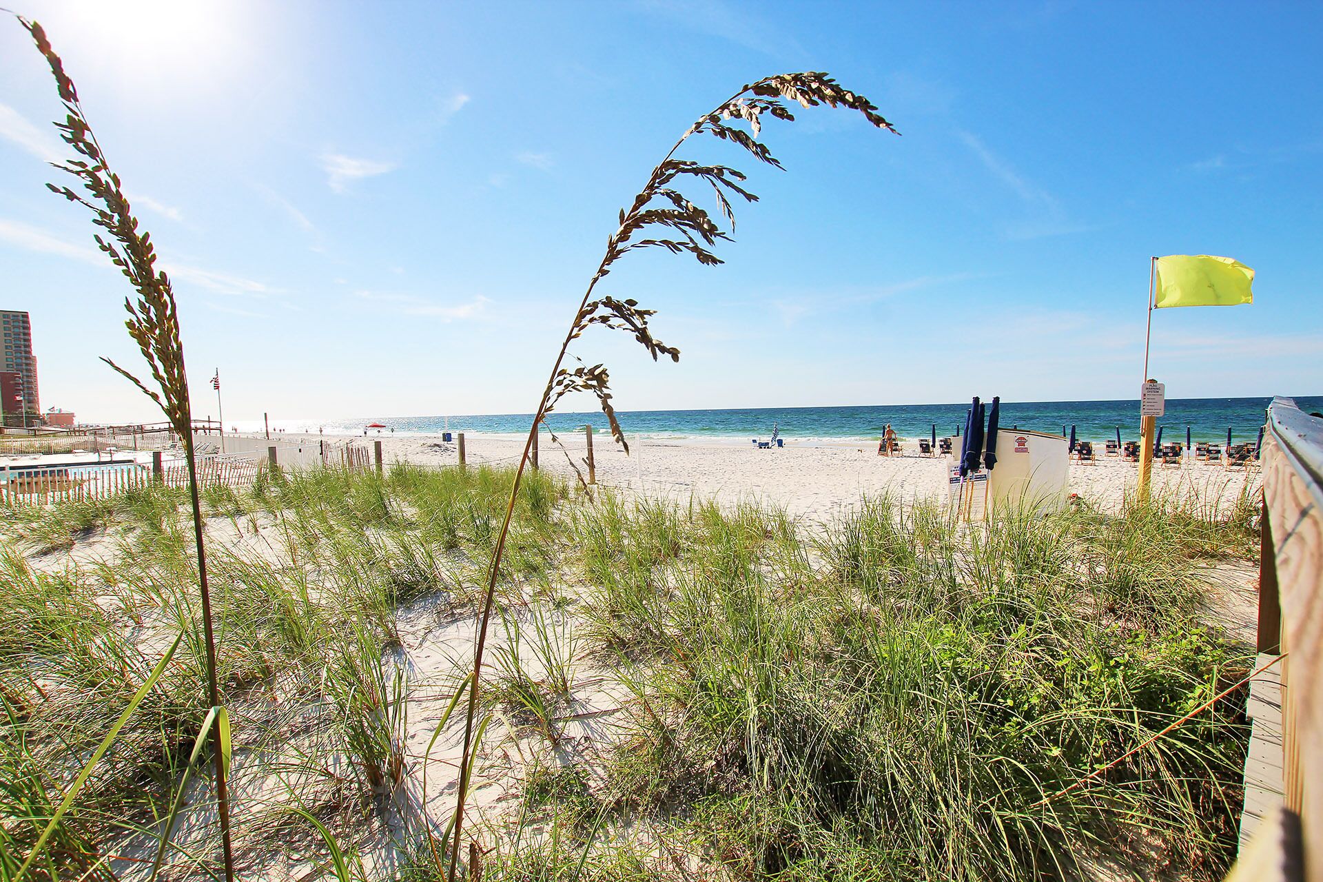 Een strand met een zandstrand, een houten hek en een gele vlag.