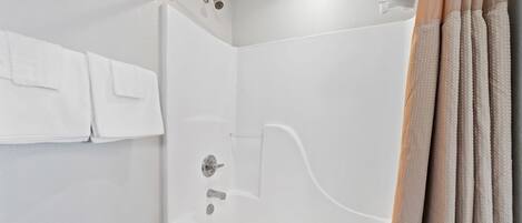 Une salle de bain moderne avec une douche à parois de verre, un porte-serviettes avec des serviettes blanches et un rideau de couleur beige.