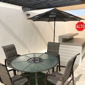 Relax outdoors with a round table and six chairs, a barbecue grill, and a shaded area.