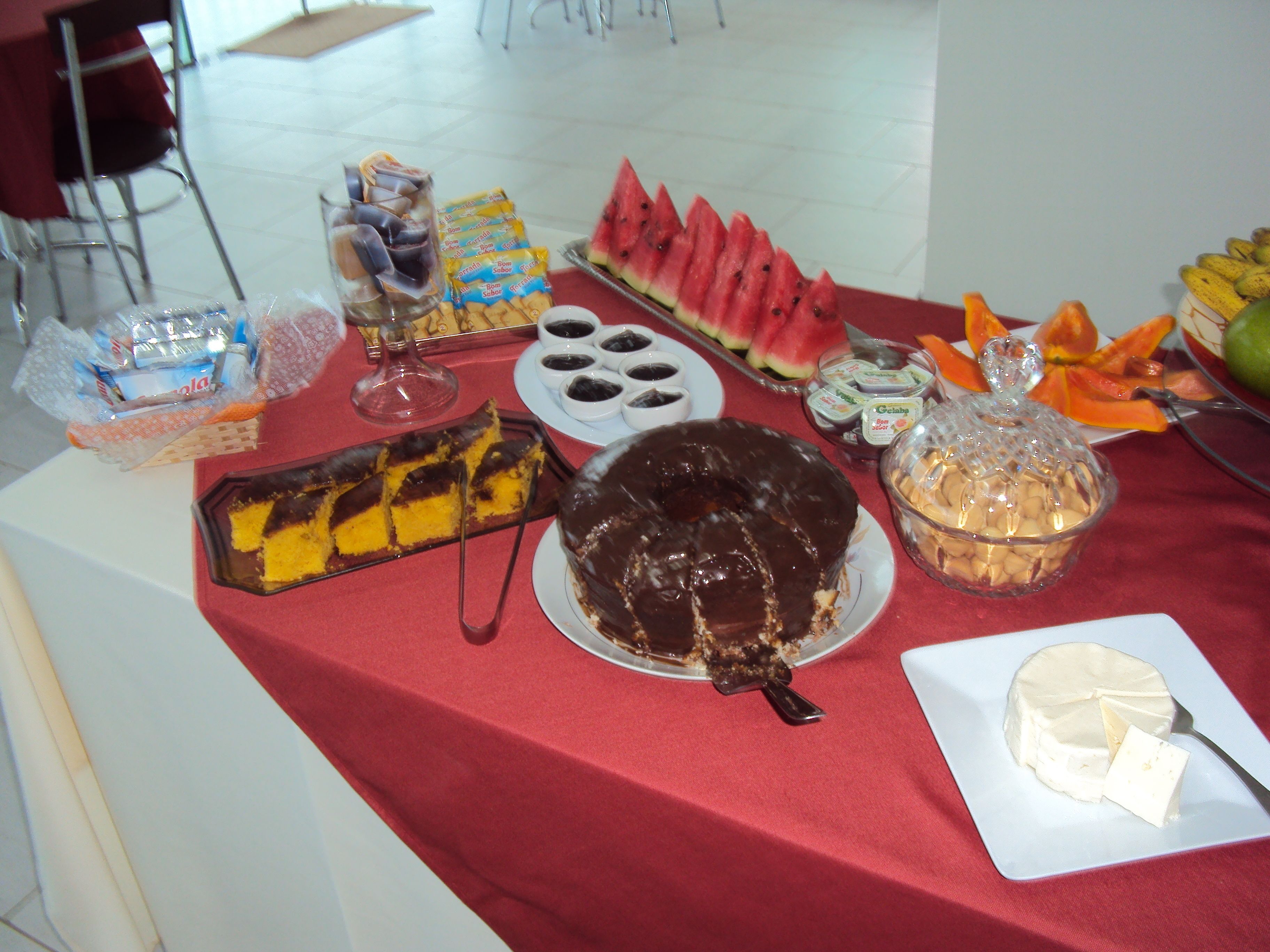 A buffet table with various food items including a chocolate cake, watermelon slices, and a variety of snacks.