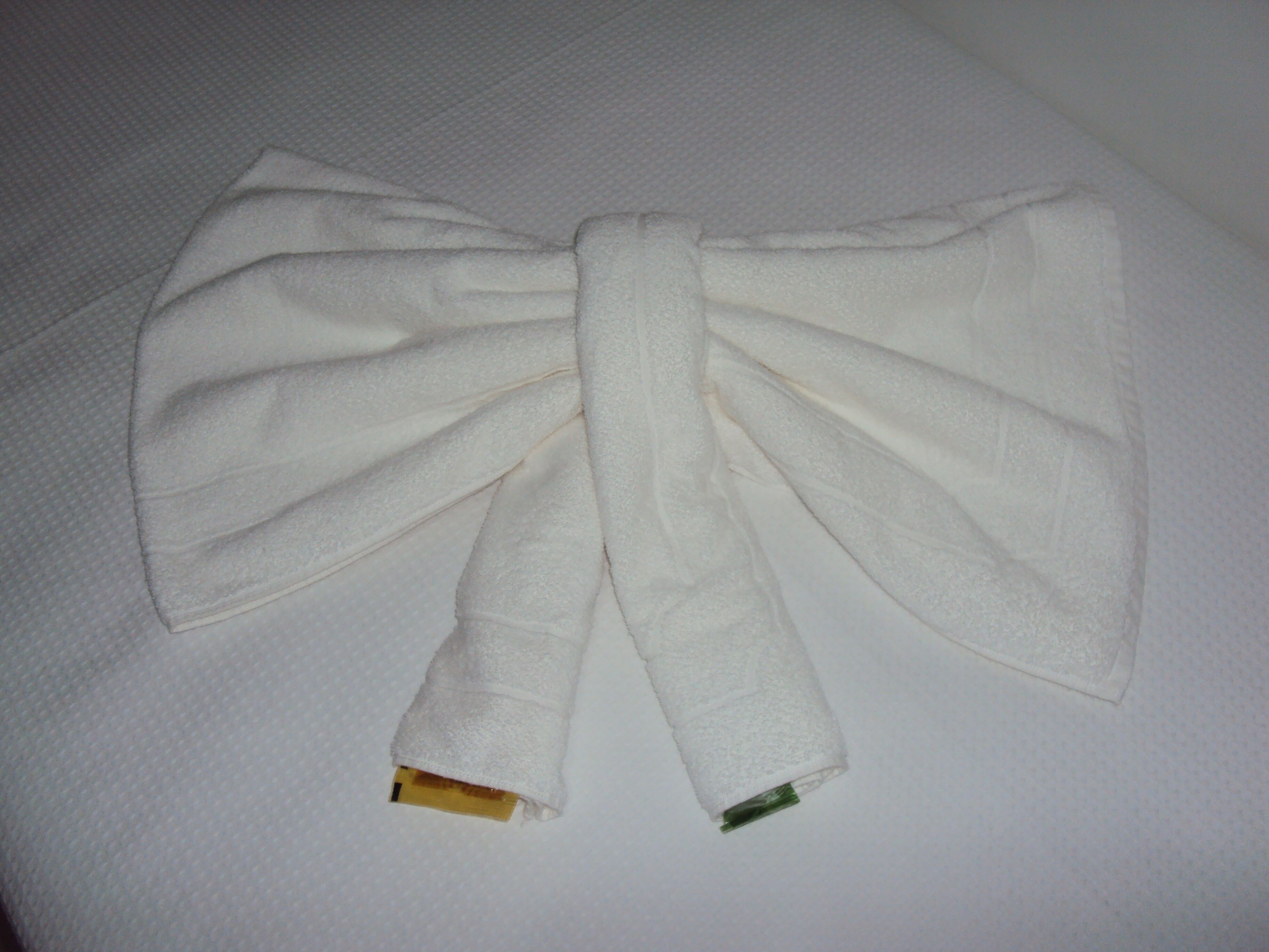 A white bow tie laid out flat on a textured surface.