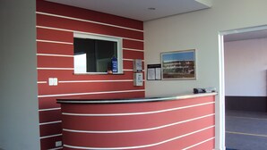 A reception desk with a curved design, a window, and a wall-mounted sign indicating payment acceptance. - Laf Hotel (Registro)