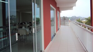 A balcony with a glass door leading to a dining area with tables and chairs. - Laf Hotel (Registro)