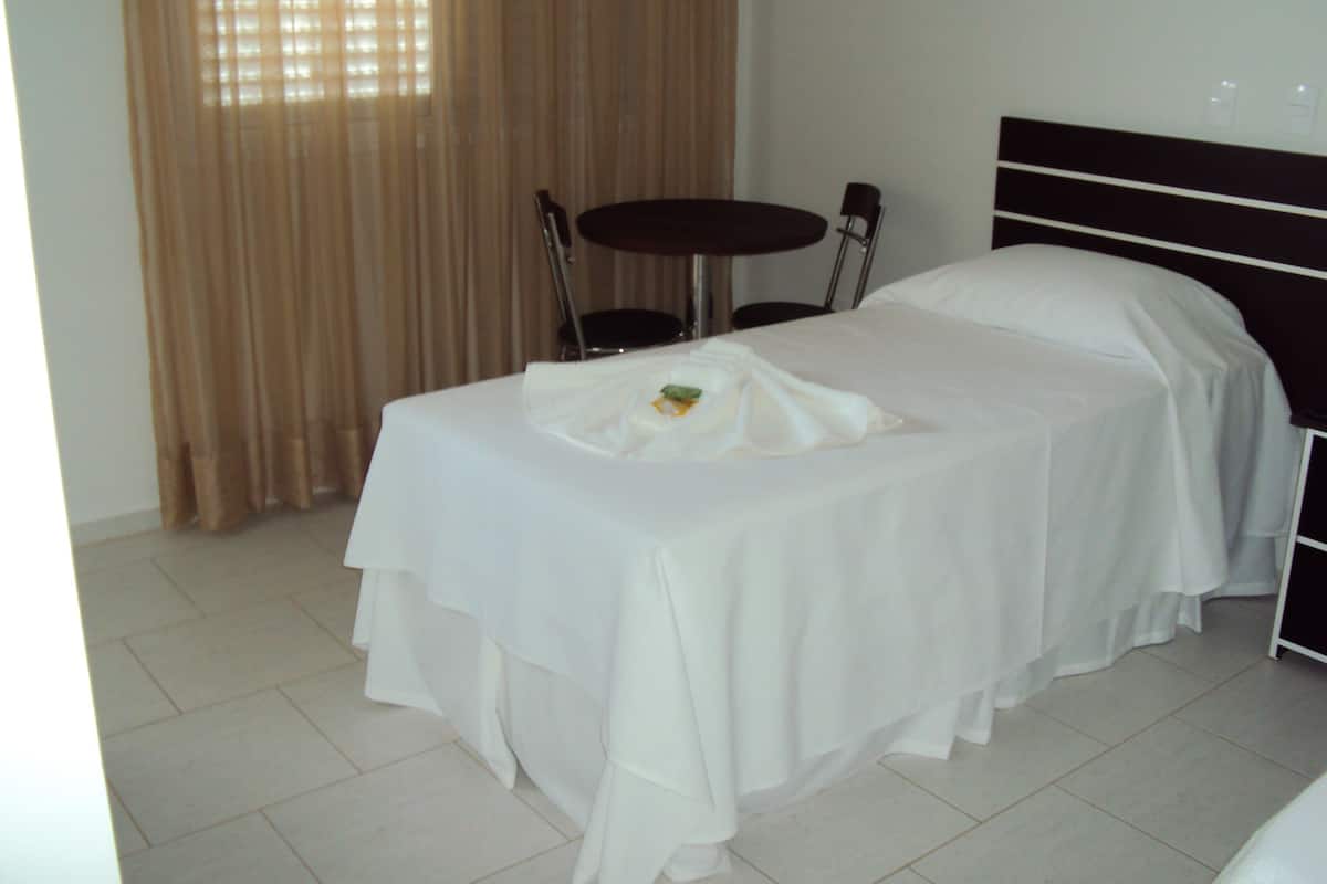 Una habitación de hotel con una cama, una mesita redonda y una silla.