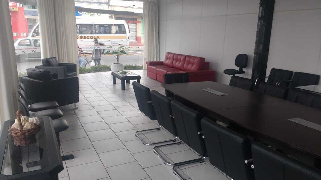 A conference room with a long table, black chairs, a red sofa, and a small coffee table.