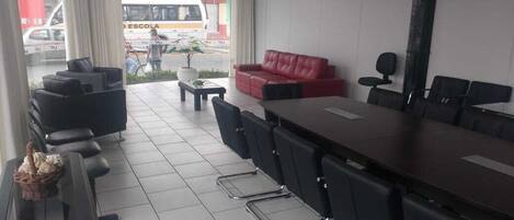 A conference room with a long table, black chairs, a red sofa, and a small coffee table.