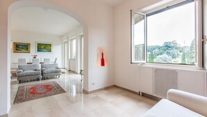 Ein modernes Wohnzimmer mit großem Fenster, Kamin und Blick ins Freie.
