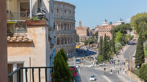 A view of the Colosseum with a street in the foreground and buildings in the background.