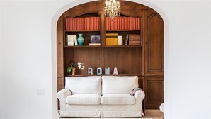 Ein weißes Sofa vor einem Bücherregal aus Holz mit Büchern und einer Vase.