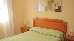 Une chambre à coucher avec un lit en bois, une table de chevet avec une lampe et deux tableaux encadrés accrochés au mur.
