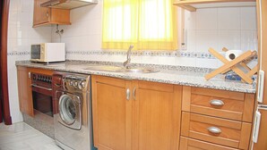 Une cuisine compacte avec des meubles en bois, un lave-linge encastré, un four à micro-ondes et un évier.