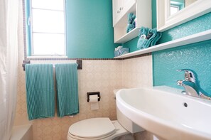Un baño con inodoro, lavamanos y perchero para toallas.
