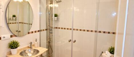 A bathroom with a glass-enclosed shower, a sink with a mirror, and a towel rack.