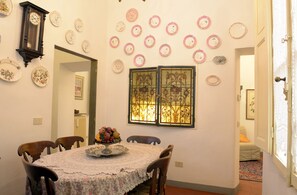 A dining area with a round table, chairs, a clock, and decorative plates on the wall. - Palazzetto dei Nobili apartment (Firenze)
