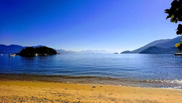 A beach with clear water, a sandy shore, and distant mountains. - Bela Casa Ilha Grande (Angra dos Reis)