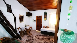 A cozy room with a wooden staircase, a dining area with a table and chairs, a sofa, and a bed. - Bela Casa Ilha Grande (Angra dos Reis)