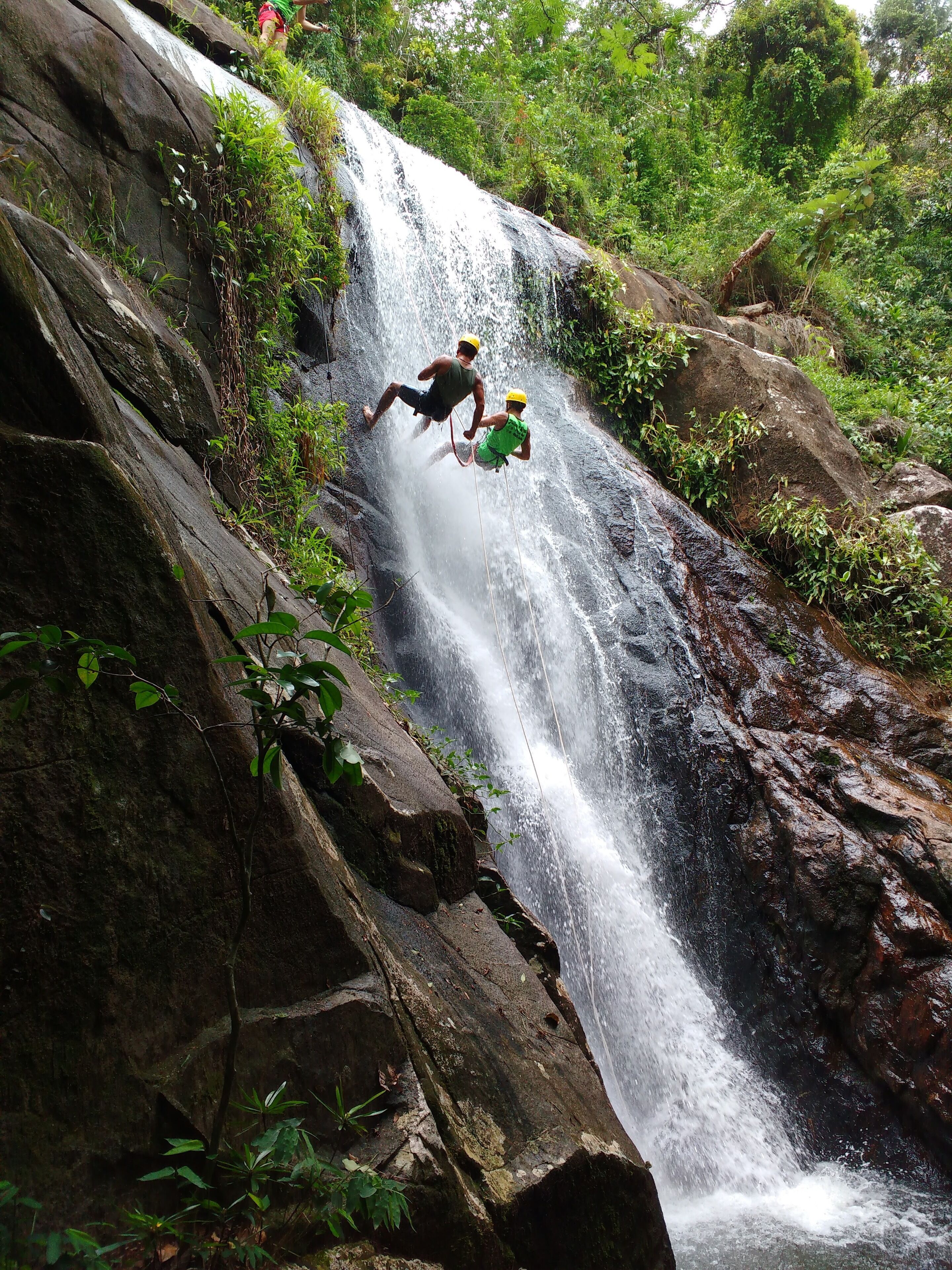 Uma cascata em ambiente natural, com terreno rochoso e vegetação.