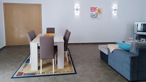 Un saló modern amb zona de menjador, un sofà, una televisió i una porta.