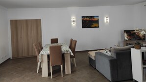 Un comedor con una mesa y sillas, un sofá, un televisor y un cuadro en la pared.