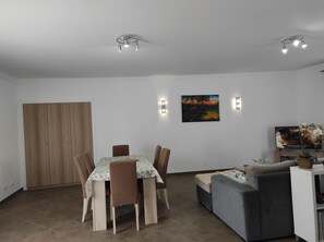 Un coin repas avec une table et des chaises, un canapé, un téléviseur et un tableau au mur.