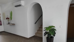 Un passadís amb una escala, una planta en test i un aire condicionat fixat a la paret.