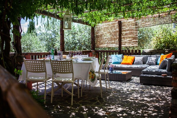 An outdoor patio with a table set for dining, surrounded by wicker furniture and a cushioned sofa. - Luxury Villa, Private Pool, Views, Barga, Tuscany. 3 ensuite Bedrooms (Barga)