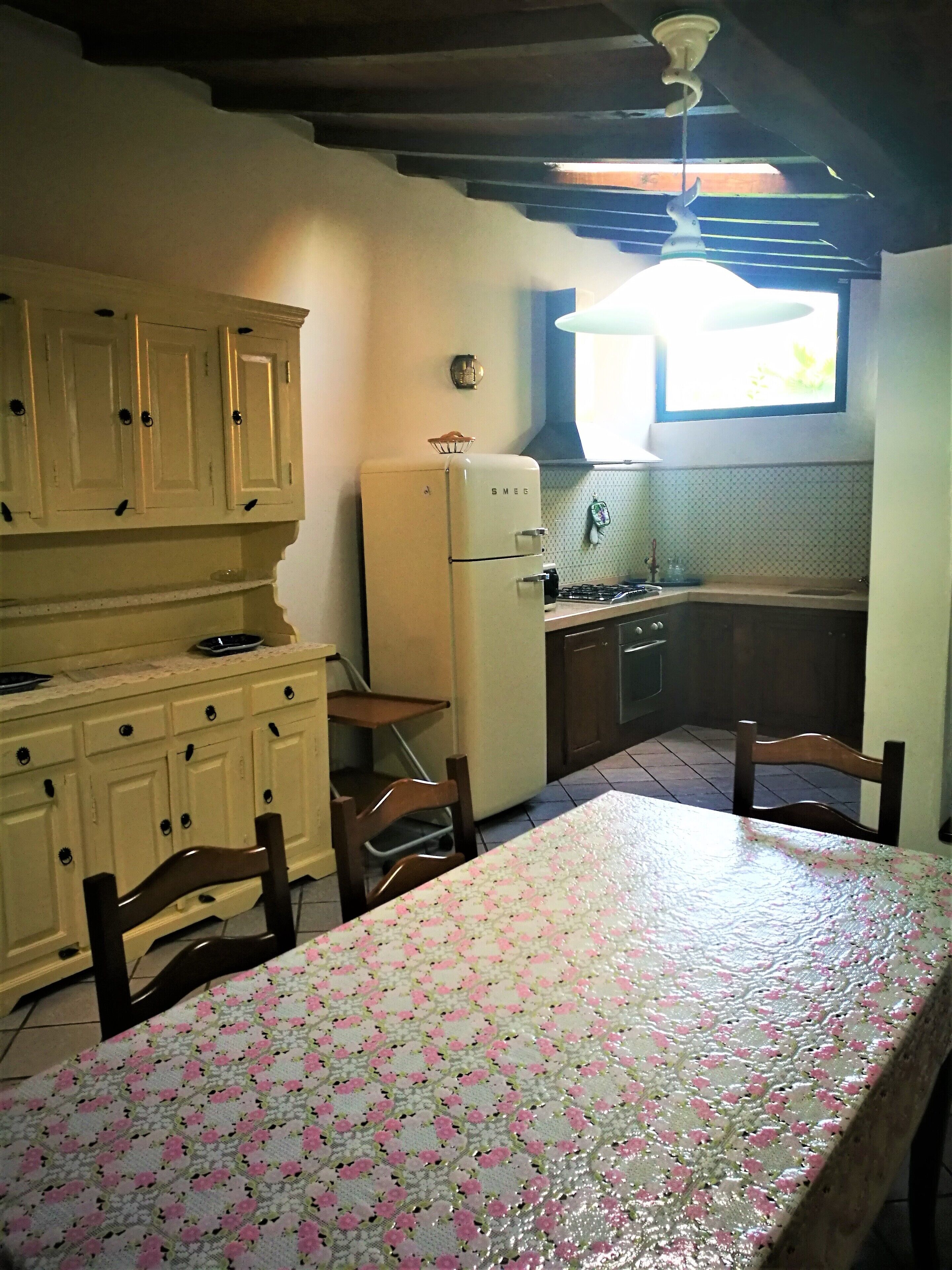 Une cuisine équipée d’un réfrigérateur, de placards et d’une table à manger avec des chaises.
