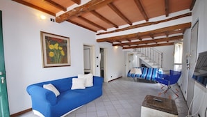A room with a blue sofa, a wooden cabinet, and a staircase.