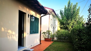 A building with a white exterior, green shutters, and a red-tiled entrance.