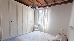 A bedroom with a bed, a nightstand, and a window with curtains.