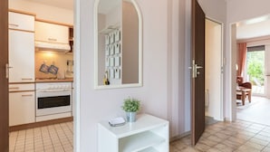 A modern kitchen with white cabinets, a stove, and a mirror above a white console table with a potted plant.
