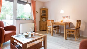 A cozy room with a dining table, chairs, a wooden cabinet, and a window with curtains.