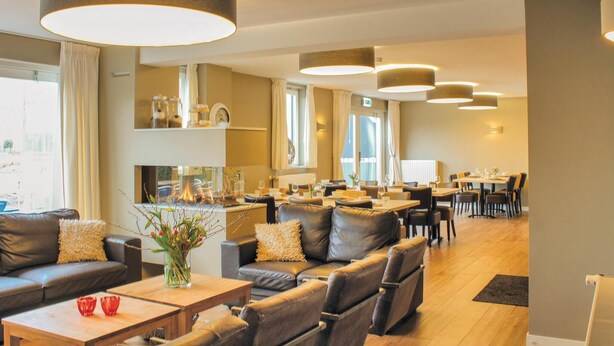 A modern hotel lobby with leather sofas, wooden tables, and pendant lighting.