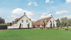 A large, modern house with a symmetrical design, featuring two main sections with pitched roofs and a central courtyard.