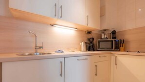 A modern kitchen with a stainless steel sink, a coffee maker, a microwave, and wooden cabinets. - Apartment "Flounder" (ID 344) - Friesenresidence (Sankt Peter-Ording)